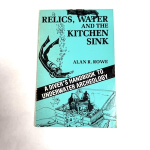May include: A vintage book titled "Relics, Water, and the Kitchen Sink" with a turquoise cover. The cover features a diver illustration and the text "A Diver's Handbook to Underwater Archeology" by Alan R. Rowe.
