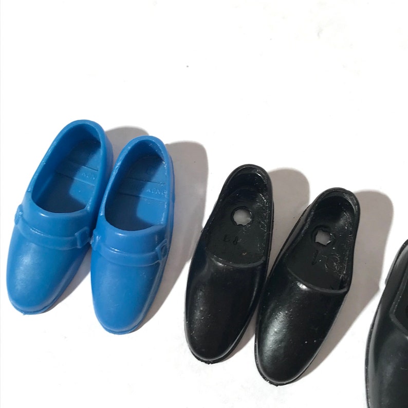 May include: Two pairs of doll shoes. One pair is blue and the other pair is black.