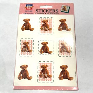 May include: Sheet of stickers featuring brown teddy bears. Each sticker has a teddy bear image, some holding a small card, set against a pink and white checkered background. The sticker sheet is labeled "STICKERS" and includes the number of sheets and stickers.
