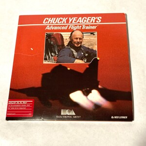 May include: A red box with the text "CHUCK YEAGER'S Advanced Flight Trainer" on the front. The box features a photo of Chuck Yeager in a cockpit. The text "APPLE II, II+, IIe, IIgs" is on the bottom left corner of the box. The text "ELECTRONIC ARTS®" is on the bottom center of the box. The text "By NED LERNER" is on the bottom right corner of the box.