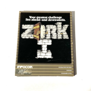 May include: A vintage game box for Zork I, an interactive fiction fantasy game for the Apple II computer. The box features a black background with a white illustration of a stone wall with a door and the word "ZORK" in large white letters. The text "Your greatest challenge lies ahead-and downwards." is printed in white at the top of the box. The box is brown with gold trim and the text "INFOCOM", "SOFTWARE FOR 10 APPLE", "INTERACTIVE FICTION", "FANTASY", and "STANDARD LEVEL" is printed in white.
