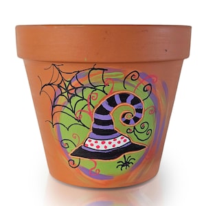 Peut inclure: Un pot de fleur en terre cuite décoré sur le thème d'Halloween. Le motif comprend un chapeau de sorcière à rayures violettes et noires, une toile d'araignée et une petite araignée. Le fond présente des tourbillons verts, violets et oranges.