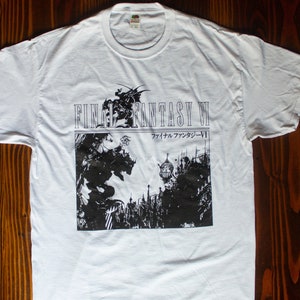 Puede incluir: Camiseta blanca con un gráfico en blanco y negro de Final Fantasy VI. El diseño incluye el título del juego y texto japonés. La camiseta tiene cuello redondo y mangas cortas.