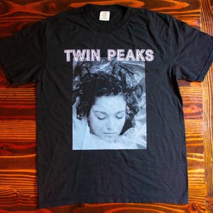May include: Black t-shirt with a white graphic print of a woman's face and the text "Twin Peaks" above the image.