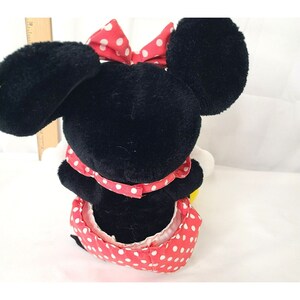 Pu&ograve; includere: Un giocattolo di peluche nero e rosso di Minnie Mouse con un vestito rosso a pois bianchi e un fiocco rosso a pois bianchi.