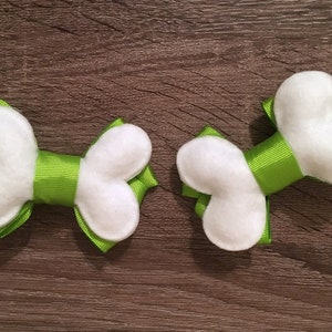 May include: Two white felt bone-shaped hair bows with green ribbon.