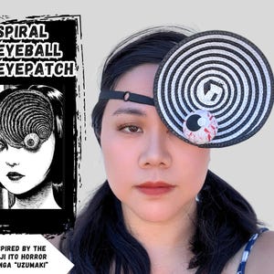 Op de afbeelding: Spiraal ooglapje geïnspireerd op de Junji Ito horror manga "Uzumaki". Het ooglapje heeft een zwart-wit spiraalontwerp en een kleine, rood-witte oogbal. De tekst "SPIRAL EYEBALL EYE PATCH" is zichtbaar.