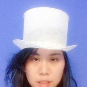 May include: A white top hat with a wide brim. The hat is made of a woven material and has a smooth, clean finish.