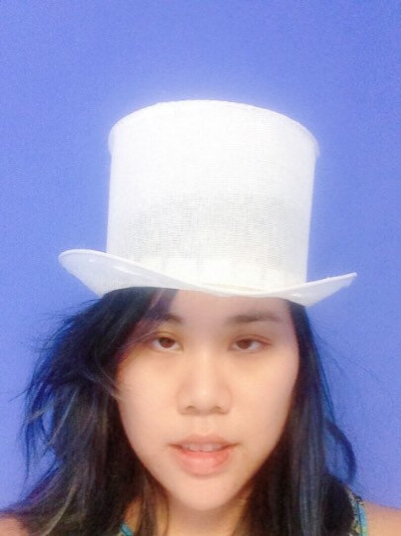 May include: A white top hat with a wide brim. The hat is made of a woven material and has a smooth, clean finish.