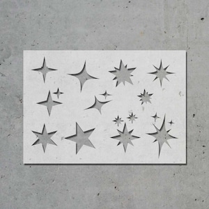 May include: A white stencil with a variety of star shapes cut out. The stencil is perfect for creating a festive design on walls, furniture, or other surfaces.