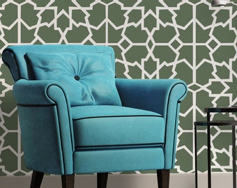May include: A teal blue armchair with a button tufted cushion sits in front of a wall with a green and white geometric pattern. The chair has black trim and wooden legs.