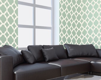 May include: A black leather sectional sofa with multiple cushions sits in front of a window with a view of a green and white patterned wall.