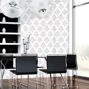 May include: A dining room with a white wall featuring a gray and white patterned wallpaper. The room has a black dining table with six black chairs. A modern chandelier hangs from the ceiling.