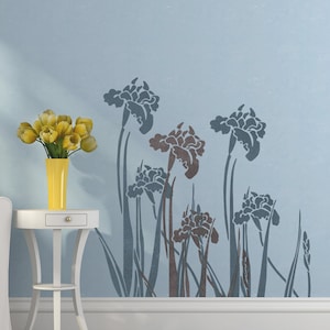 May include: A stencil featuring a design of stylized iris flowers with long stems and leaves. The stencil is on a light blue background.