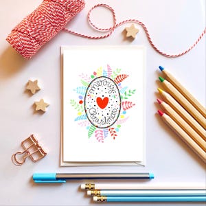 Corona navideña de arcoíris y corazón sobre cartulina blanca. Corona de hojas de invierno. Feliz Navidad. Corona de muérdago y acebo.