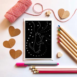 Chat noir jouant avec des étoiles, carte de voeux. Carte d'Halloween.