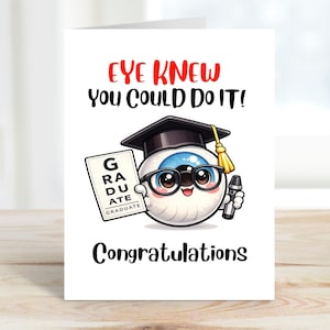 Może przedstawiać: Biała kartka z gratulacjami z okazji ukończenia studiów z napisem "EYE KNEW You Could Do It!" w kolorze czerwonym i czarnym. Karta przedstawia kreskówkowe oko w czapce absolwenta i okularach, trzymające tablicę "GRADUATE" i długopis. Słowo "Gratulacje" jest napisane na dole.