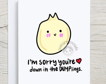 May include: A white greeting card with a cartoon dumpling illustration. The dumpling is yellow with a black outline, pink cheeks, and a smiling face. The text reads, "I'm sorry you're down in the DUMPLINGS."