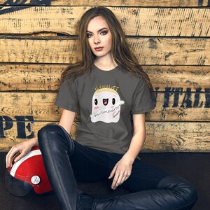 May include: A charcoal grey t-shirt with a cartoon ghost wearing a crown and the text "Not Real, Yet" and "Y'all is Good, I'll Not Do Drugs".