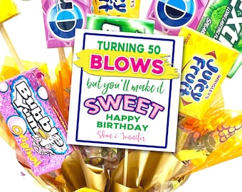May include: A colorful birthday card with the text "Turning 50 Blows but you'll make it Sweet Happy Birthday Shan & Jennifer" surrounded by various candy and gum wrappers.