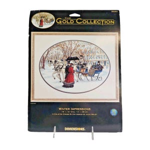 May include: A Dimensions The Gold Collection counted cross stitch kit titled Winter Impressions. The packaging features an oval illustration of a horse-drawn carriage in a snowy landscape, measuring 16 inches by 12 inches, by artist Alan Maley.
