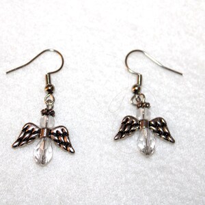 May include: A pair of silver angel wing earrings with clear crystal accents.