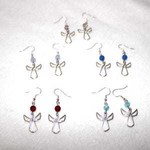 Peut inclure: Boucles d'oreilles en forme d'ailes d'ange argentées avec des perles de différentes couleurs. Les perles sont lavande, bleu, rouge et turquoise.