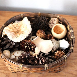May include: A woven basket filled with natural elements, including pinecones, dried flowers, and a small wooden bowl.