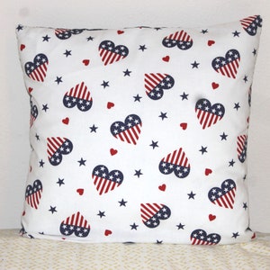May include: White pillow with a red, white, and blue heart pattern. Each heart features a stylized American flag design.