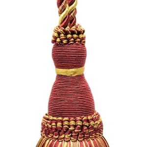 Puede incluir: Una borla decorativa en burdeos y dorado. La borla tiene un lazo de cordón trenzado, un cuerpo bulboso y una larga borla. Los colores son ricos y el diseño es ornamentado, adecuado para cortinas o decoración del hogar.