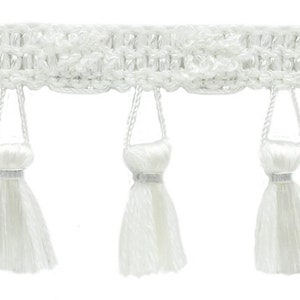 May include: White fringe trim with a woven top and dangling tassels. The trim has a textured design with small, decorative tassels hanging below. The tassels have a silver band at the top. Suitable for craft and sewing projects.