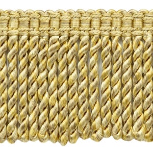 Può includere: Un primo piano di un bordino di frangia ritorto dorato e beige. La frangia è realizzata in un tessuto morbido e tessuto e ha un leggero bagliore.