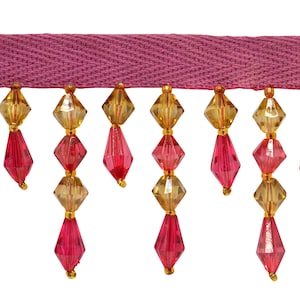 Puede incluir: Borde de cuentas rosa y dorado con un respaldo de tela rosa. Las cuentas son facetadas y tienen forma de lágrima.