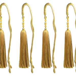 May include: Four gold tassel tiebacks with a twisted rope design. Each tieback has a gold tassel with a beaded accent.