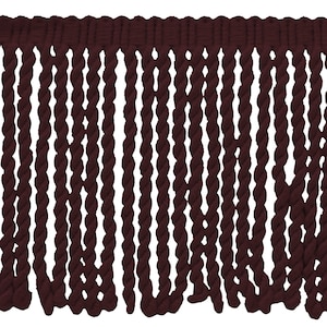 May include: A close-up of a dark brown twisted fringe trim. The fringe is made of a soft, woven material and has a slightly textured appearance.