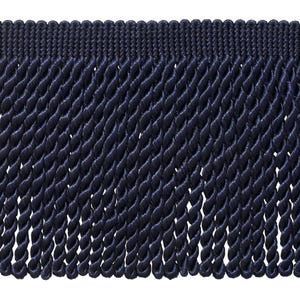 May include: A dark navy blue fringe trim featuring a horizontal woven header band with a series of hanging, twisted cord tassels. The individual tassels are uniform in length and thickness, creating a dense, textured, and repeating vertical pattern.