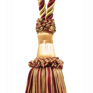 May include: A red, gold, and green tassel with a braided rope cord. The tassel is made of multiple strands of yarn and has a decorative knot at the top.