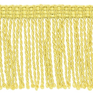 May include: A yellow twisted fringe trim with a woven top edge. The fringe is approximately 1 inch in length.
