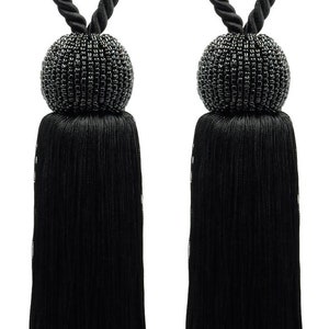May include: Two black tassel tiebacks with a beaded ball at the end. The tassels are made of a soft, silky material and are approximately 45 cm long.