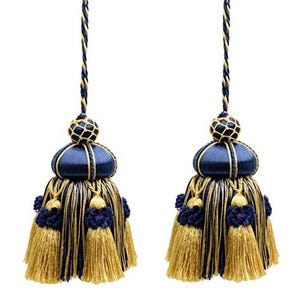 Puede incluir: Dos borlas decorativas con detalles en azul marino y dorado. Cada borla presenta una parte superior en forma de cúpula azul marino, un cordón trenzado dorado y azul marino, y un grupo de borlas doradas. Para la decoración del hogar.