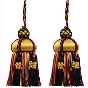 Peut inclure: Deux glands décoratifs aux couleurs or, noir et rouge. Chaque gland présente un dessus doré en forme de dôme, une frange noire et rouge et un nœud décoratif. Les glands sont suspendus par un cordon torsadé.