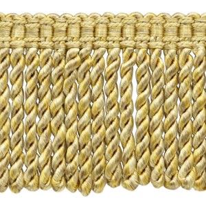 Può includere: Primo piano di un bordo di frange dorate decorative. Il bordo presenta una sezione superiore intrecciata con una serie di fili ritorti a forma di corda che pendono al di sotto. Il colore è un oro caldo e chiaro, adatto a vari progetti artigianali e di design.
