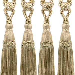 May include: Set of four beige tassel tiebacks with a braided rope design. The tassels are made of a soft, fringed material and have a decorative knot at the top.