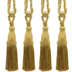 Può includere: Set di quattro fermatenda a nappina dorati con un design a corda. Le nappine sono realizzate in un tessuto morbido e spazzolato e hanno un fondo a frangia.