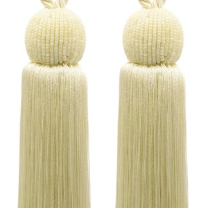 Peut inclure: Une paire de jetés de rideaux en pompons de couleur crème avec des boules perlées. Les pompons sont faits de longues et fines mèches de tissu et les boules sont faites de petites perles blanches.