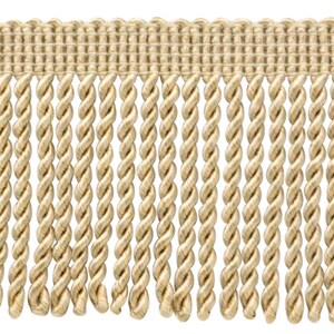 May include: A close-up of a beige twisted fringe trim. The fringe is made of a soft, woven fabric and has a subtle sheen.