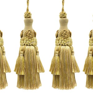 May include: Four gold decorative tassels with detailed knot and fringe elements. Each tassel features a rounded top, a central knot design, and a long, flowing fringe. The tassels are suspended by a twisted gold cord.