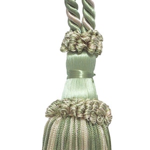 May include: A decorative curtain tieback featuring a large tassel. The tieback is made of twisted rope in shades of green and beige, with a matching tassel at the bottom. The tassel is approximately 8 inches long.