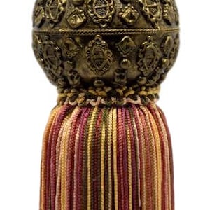 Peut inclure: Un pompon décoratif avec une boule en métal doré et une frange multicolore. La frange est composée de plusieurs couleurs, dont le rouge, le marron et l'or.