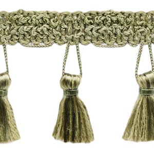 May include: A close-up of a gold fringe trim with tassels. The fringe is made of a woven fabric and has a subtle sheen. The tassels are approximately 2.5 cm long and are evenly spaced.